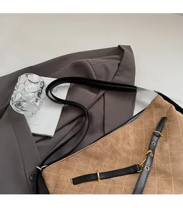 Detail of brown suede tote with diamond quilting and black adjustable leather strap