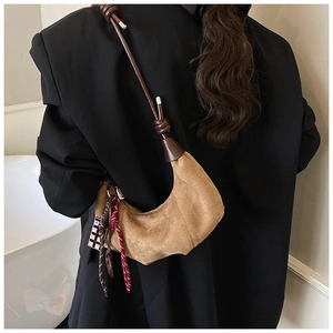 Sac croissant en daim marron porté sur un blazer noir pour un look d'hiver élégant