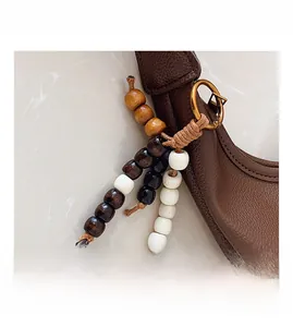 Detail of brown pebbled leather bucket bag with multi-tone wooden bead charms and gold hardware