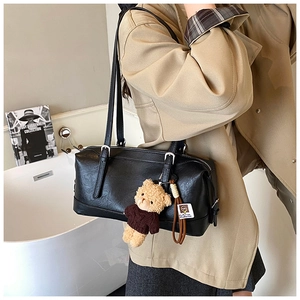 Detail of black faux leather Boston bag with cute teddy bear charm and dual handles