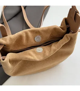 Détail de la boucle magnétique et de la poche zippée de ce sac à bandoulière en daim brun