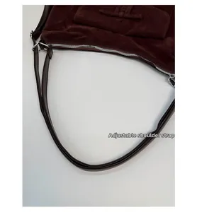 Detail of adjustable leather shoulder strap and silver zipper on brown suede hobo bag