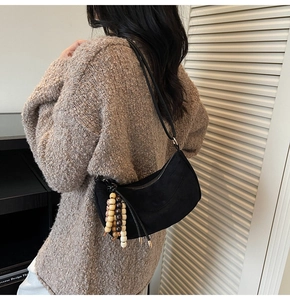 Detail of black suede hobo bag with unique wooden bead charm and zip closure