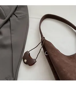 Gros plan du sac porté épaule en daim mat marron avec petit charme et boucle en argent