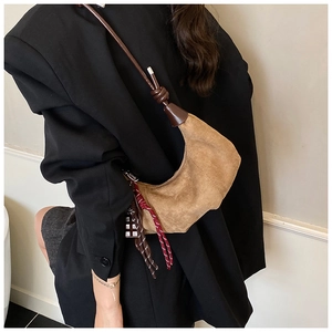 Détail du sac hobo en daim marron avec cordon décoratif et breloque en chocolat