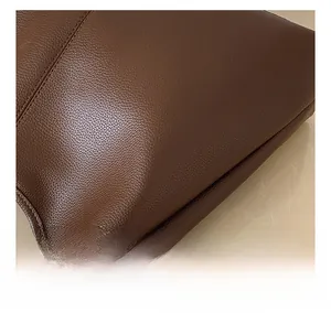 Macro shot of dark brown pebbled leather texture with neat stitching on tote bag