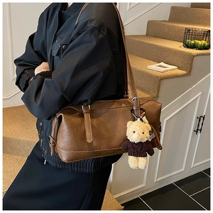 Deep brown retro cylinder shoulder bag with plush bear charm and silver hardware detail