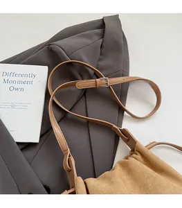 Détail de la bandoulière réglable et texture suède marron sur le sac à bandoulière chic