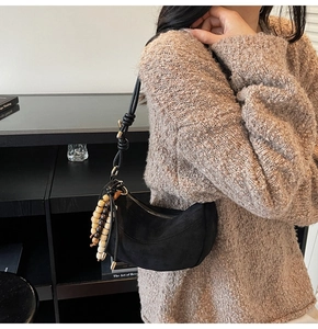Dettaglio borsa hobo in camoscio nero con nappe di perline di legno e tracolla annodata