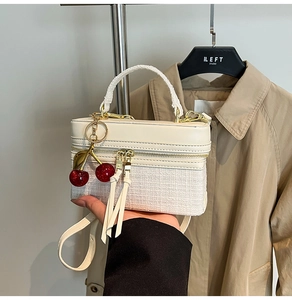 Detail of tweed and leather contrast handbag featuring cherry charm and double zippers