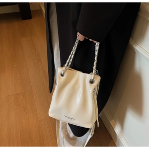 Detail of cream white bucket bag featuring drawstring closure and chain handle strap