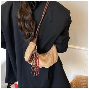 Détails d'un sac demi-lune en daim marron avec pendentifs chocolat et bretzel