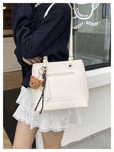 Detail of cream tote bag with lychee texture featuring a cute bear charm and silk scarf
