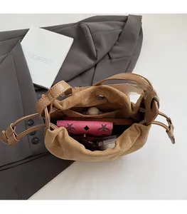 Vue intérieure du sac seau en daim marron montrant la grande capacité et la poche zippée