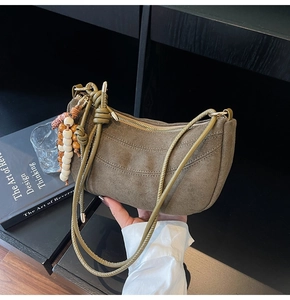 Dettaglio borsa vintage in pelle scamosciata verde oliva con cinturino a nodo e perline