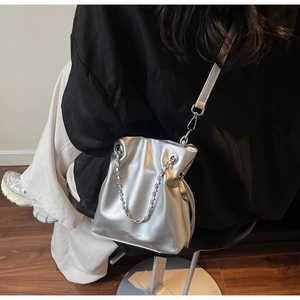 Detail of silver metallic bucket bag with embossed Fashion & Bags text on the front