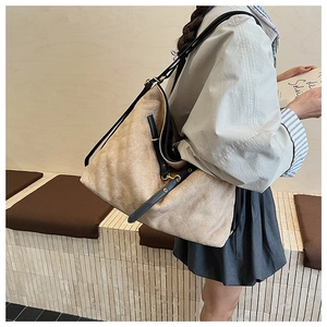 Detail of beige quilted hobo bag with black leather strap and metal buckle on shoulder