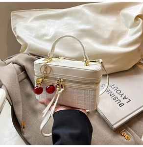 Detailed view of cream tweed patchwork handbag with cherry charm and leather strap