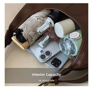 Detail showing high-capacity interior of brown leather tote bag with daily essentials