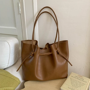 Detailed close-up of dark brown faux leather tote with drawstring closure and knots