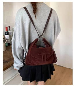 Detail of dark brown suede backpack with bow design and leather straps worn by a model