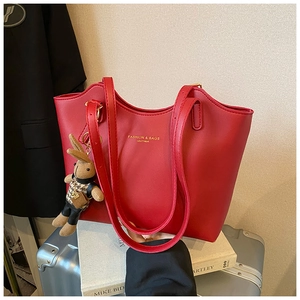 Détail d'un grand sac cabas en cuir rouge avec logo doré et pendentif lapin mignon