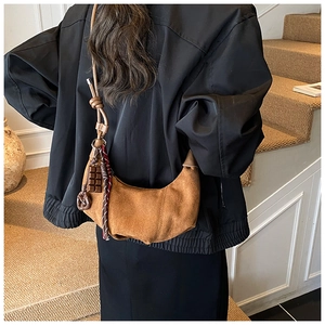 Détail du sac croissant en daim marron avec pendentif chocolat et ruban à carreaux