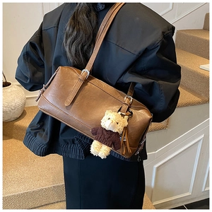 Retro brown bowling bag detail with adjustable straps and cute plush bear charm