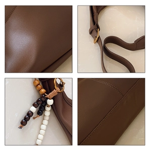 Close-up of litchi texture leather, neat stitching, and beaded tassel on dark brown tote