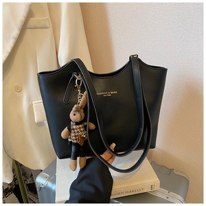 Détail d'un grand sac cabas en cuir noir avec lettrage doré et charme lapin en peluche