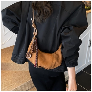 Détail du sac croissant en daim marron avec pendentif chocolat et glands tissés