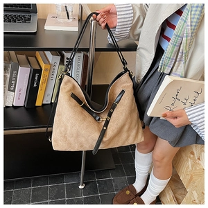 Detail of beige quilted tote bag with black leather straps and large interior capacity
