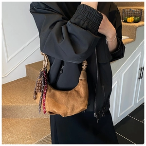 Détail du sac demi-lune en daim marron avec breloque chocolat et cordon tressé coloré
