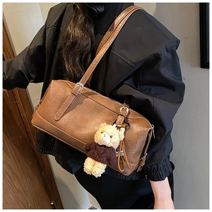 Brown vintage Boston bag with a cute teddy bear pendant shown in a stylish street style view