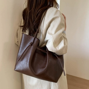 Detail of soft leather tote bag with side drawstring knot and natural matte texture