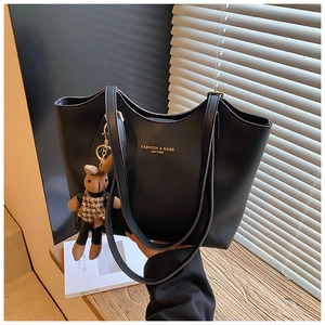 Detail of black faux leather tote bag with gold lettering and cute bunny doll charm