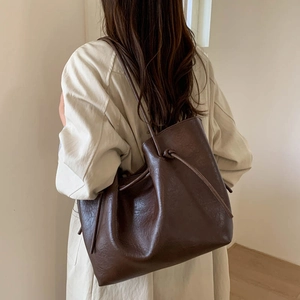 Close-up of a large dark brown tote bag with drawstring detail and pebble grain texture