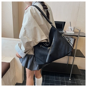 Detail of black quilted shoulder bag featuring durable fabric and metal buckle