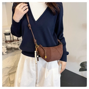 Detail of suede crescent bag featuring retro wooden bead pendant and slim leather strap