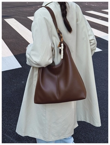 Deep brown pebble leather hobo bag with colorful bead pendant worn by model outdoors