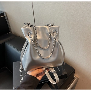 Detailed close-up of a silver metallic bucket bag featuring drawstring and chain strap