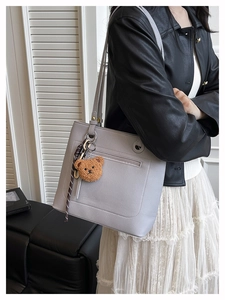 Close-up of light purple textured leather tote bag with cute bear charm and silk ribbon