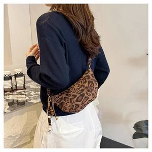 Detail of leopard print crescent bag featuring stitched seams and wooden bead charms