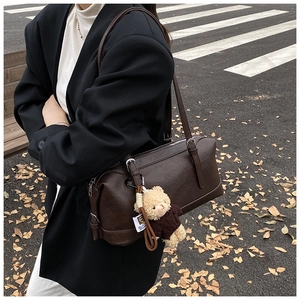 Detail of dark brown vintage shoulder bag with a cute bear charm on autumn street