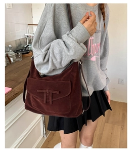Detail of vintage burgundy suede tote bag with front flap pocket and brown leather strap