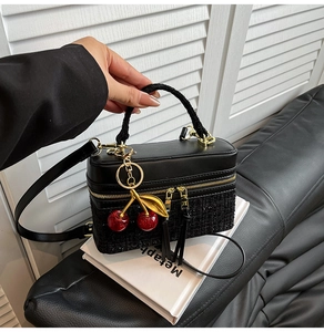 Top view of black tweed handbag with golden cherry charm and premium dual zippers