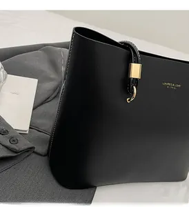 Close-up of black leather tote bag featuring white contrast stitching and gold logo detail