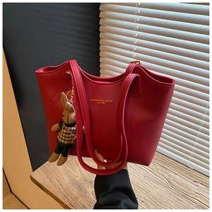 Close-up of red PU leather tote bag with gold text and cute rabbit pendant detail