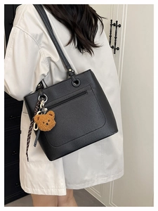 Detail view of black lychee leather tote bag with back zipper pocket and teddy bear charm