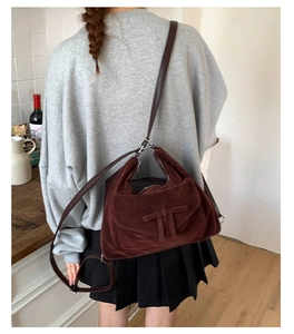 Close-up of burgundy suede crossbody bag with vintage double T leather applique detail